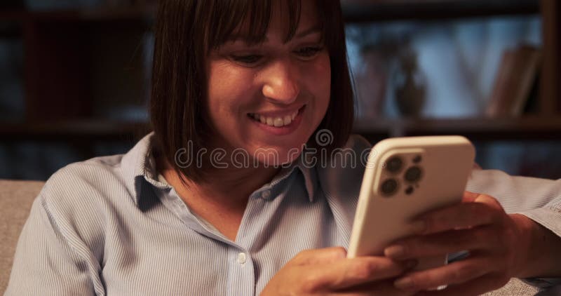 πορτρέτο χαμογελαστής καυκάσης γυναίκας που γράφει στο τηλέφωνο στον καναπέ του καθιστικού