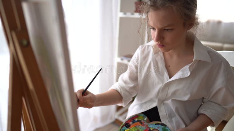 πορτραίτο νεαρής καλλιτέχνιδας από την Καυκάσια που ζωγραφίζει στον πίνακα ζωγραφικής στο σπίτι. ελκυστική εικόνα ζωγραφικής γυναι