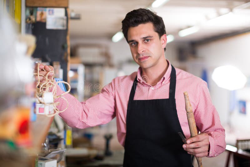 Portrait of craftsman with tool in hand near shelves in carpentry. Portrait of craftsman with tool in hand near shelves in carpentry