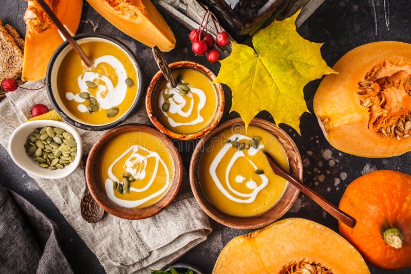 Autumn pumpkin soup puree with cream in cups, the autumn scenery. Healthy vegan food concept. Autumn food concept. Autumn pumpkin soup puree with cream in cups, the autumn scenery. Healthy vegan food concept. Autumn food concept.