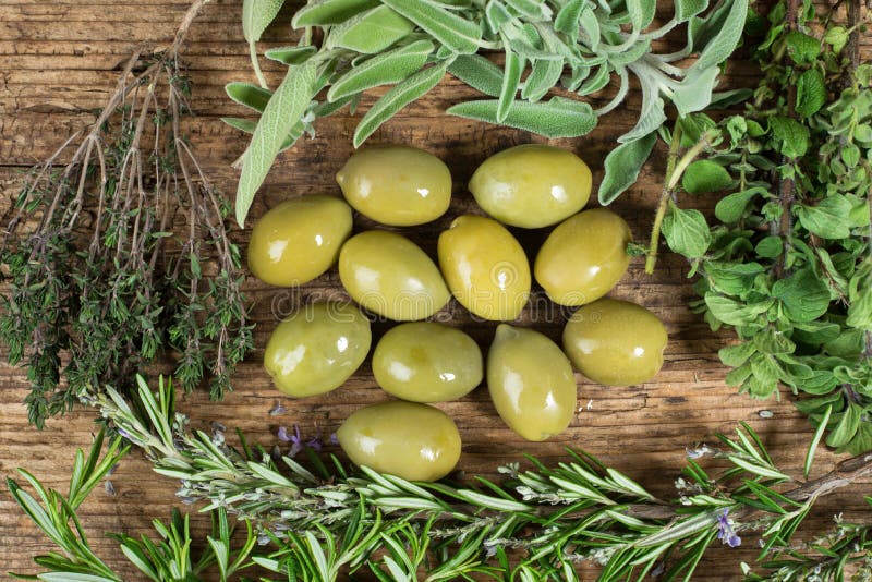 Πράσινες ελιές με διάφορα χορτάρια γύρω στον ξύλινο πίνακα στοκ φωτογραφία με δικαίωμα ελεύθερης χρήσης Πράσινες ελιές με διάφορα χορτάρια γύρω στον ξύλινο πίνακα στοκ φωτογραφία με δικαίωμα ελεύθερης χρήσης