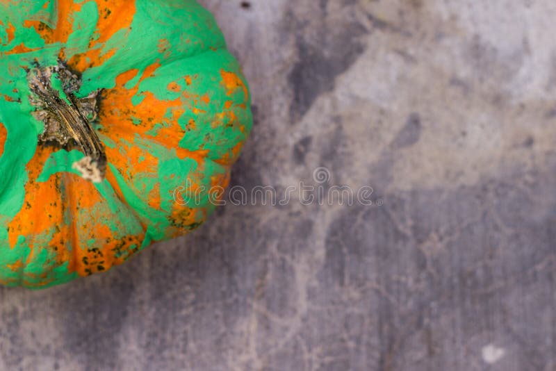 An orange pumpkin painted green, sitting on concrete. An orange pumpkin painted green, sitting on concrete.