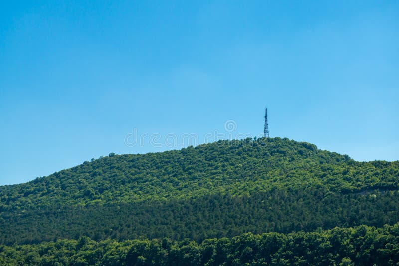 Πράσινο βουνό δίπλα στη θάλασσα με το ραδιο πύργο στην κορυφή στοκ εικόνες Πράσινο βουνό δίπλα στη θάλασσα με το ραδιο πύργο στην κορυφή στοκ εικόνες