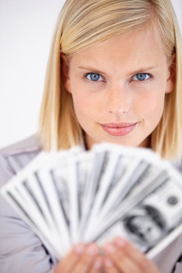 A woman holding up a wad of cash with a challenging look in her eyes. A woman holding up a wad of cash with a challenging look in her eyes.