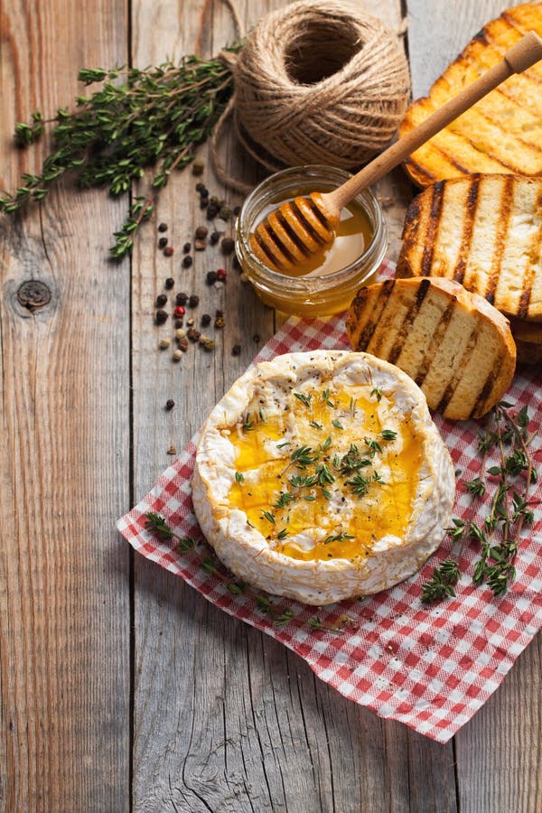 Πραγματικό Camembert από τη Γαλλία με το θυμάρι, το μέλι και το ψημένο ψωμί στον παλαιό ξύλινο αγροτικό πίνακα Μαλακό τυρί σε ένα στοκ εικόνες Πραγματικό Camembert από τη Γαλλία με το θυμάρι, το μέλι και το ψημένο ψωμί στον παλαιό ξύλινο αγροτικό πίνακα Μαλακό τυρί σε ένα στοκ εικόνες
