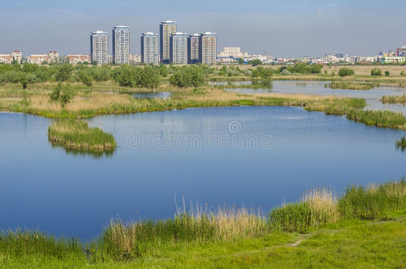 City suburbs with ecosystem Vacaresti Lake near south-eastern Bucharest with tall residential buildings on May 7, 2014 in Bucharest. Also known as the Delta of Bucharest, Vacaresti lake is a strange, intriguing raw nature island between communist blocks of flats in a southern district of Bucharest, covering around 200 hectares, including some 80 hectares of water; a stable ecosystem consisting of fish, wild ducks, swans, lizards and gulls where during the summer nest over 90 species of wild birds. City suburbs with ecosystem Vacaresti Lake near south-eastern Bucharest with tall residential buildings on May 7, 2014 in Bucharest. Also known as the Delta of Bucharest, Vacaresti lake is a strange, intriguing raw nature island between communist blocks of flats in a southern district of Bucharest, covering around 200 hectares, including some 80 hectares of water; a stable ecosystem consisting of fish, wild ducks, swans, lizards and gulls where during the summer nest over 90 species of wild birds.