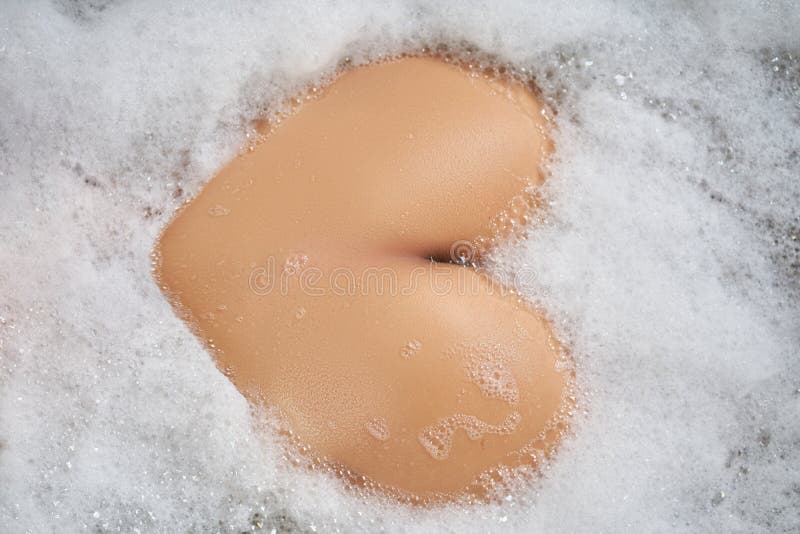 Προβολή από επάνω Υπέροχο γυναικείο στήθος σε μια λευκή μπανιέρα με αφρό