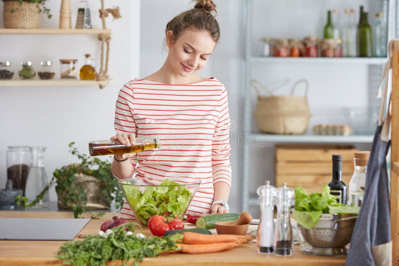 Woman adding olive oil to her healthy salad. Woman adding olive oil to her healthy salad