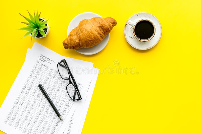 Πρόγευμα στην αρχή με croissant και τον καφέ στο γραφείο εργασίας με τα έγγραφα και τα γυαλιά στην κίτρινη τοπ άποψη υποβάθρου στοκ φωτογραφία με δικαίωμα ελεύθερης χρήσης Πρόγευμα στην αρχή με croissant και τον καφέ στο γραφείο εργασίας με τα έγγραφα και τα γυαλιά στην κίτρινη τοπ άποψη υποβάθρου στοκ φωτογραφία με δικαίωμα ελεύθερης χρήσης