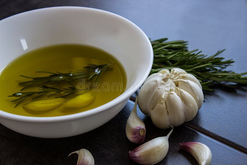 Πρόσθετο παρθένο ελαιόλαδο, που αρωματίζεται με το σκόρδο και το δεντρολίβανο στοκ εικόνες
