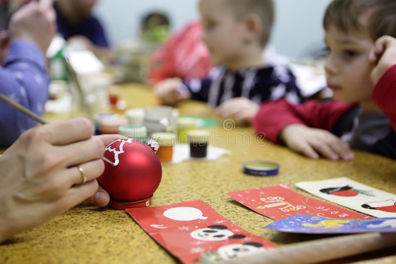 Πρόσωπο που χρωματίζει την κόκκινη σφαίρα Χριστουγέννων στοκ εικόνες