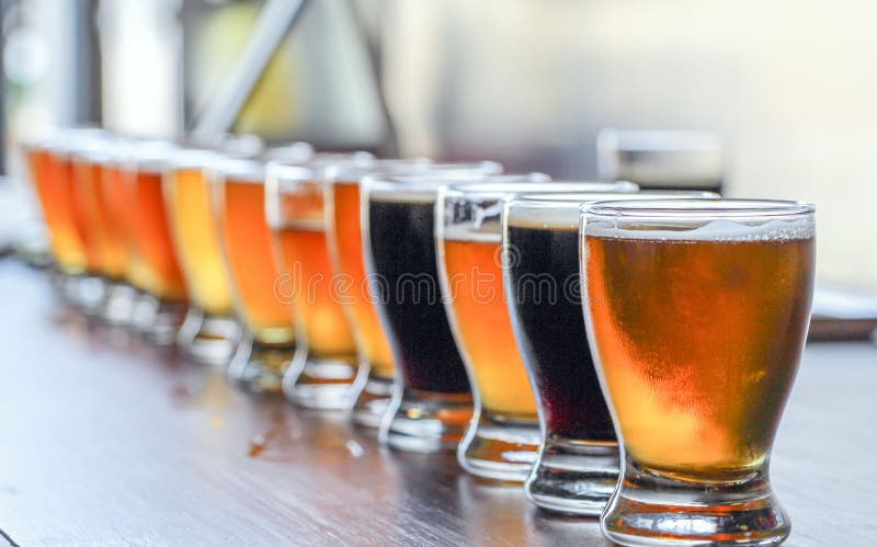 A Craft Beer Tasting Flight Sample of Many Beers Are On Display on a Bar Counter. A Craft Beer Tasting Flight Sample of Many Beers Are On Display on a Bar Counter.