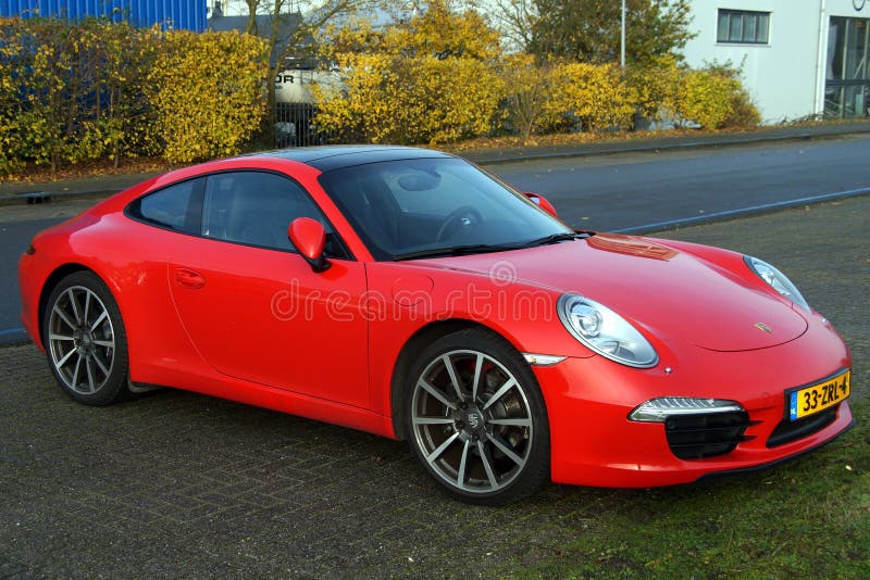 Almere Poort, Flevoland, The Netherlands - November 14, 2014: A fire red German manufactured Porsche 911 Carrera sports car parked in a parking space. Almere Poort, Flevoland, The Netherlands - November 14, 2014: A fire red German manufactured Porsche 911 Carrera sports car parked in a parking space.