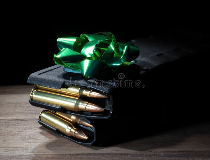 Green bow on top of two loaded high capacity AR-15 magazines on a table as a gift for a gun owner. Green bow on top of two loaded high capacity AR-15 magazines on a table as a gift for a gun owner