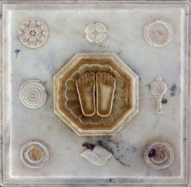 This is a traditional shrine in India representing the feet of the guru, the teacher who removes ignorance. Surrounded by important religious symbols the carving is made in marble. The feet are a representation of the one who has succeeded in walking the path and reaching the goal of enlightenment nirvana. This is a traditional shrine in India representing the feet of the guru, the teacher who removes ignorance. Surrounded by important religious symbols the carving is made in marble. The feet are a representation of the one who has succeeded in walking the path and reaching the goal of enlightenment nirvana