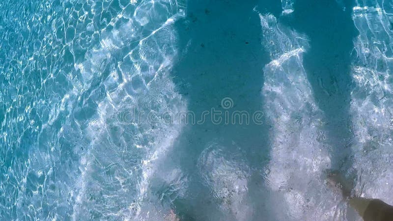 πόδια και πόδια ενός ζευγαριού που περπατάει στις λευκές μαλδίβες και παραλία.