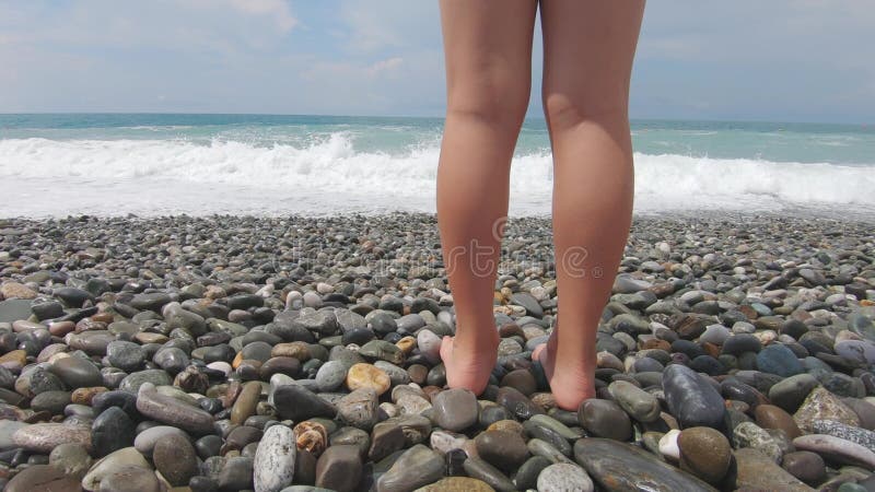 πόδια μιας νεαρής κοπέλας στην παραλία την ημέρα. νεαρή κοπέλα που περπατάει στη θάλασσα.