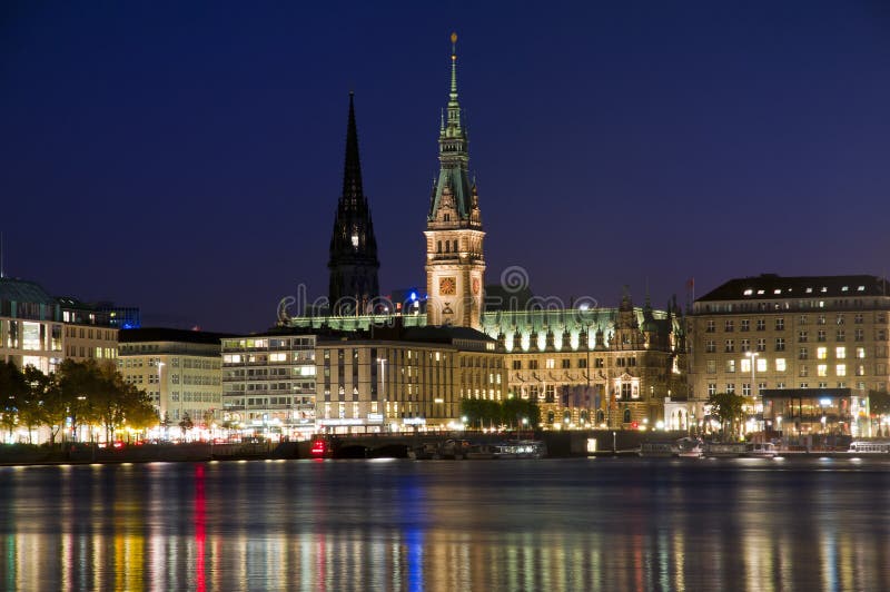 The Hamburg town hall in downtown Hamburg at the Binnenalster lake. In the background the Nikolai church, once a cathedral, destroyed in WWII and since then it's a war memorial, with only the spire remaining. The Hamburg town hall in downtown Hamburg at the Binnenalster lake. In the background the Nikolai church, once a cathedral, destroyed in WWII and since then it's a war memorial, with only the spire remaining.