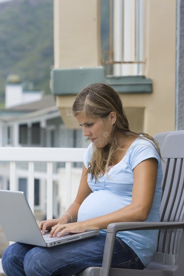 A pregnant woman searches online from her laptop computer while on vacation. A pregnant woman searches online from her laptop computer while on vacation