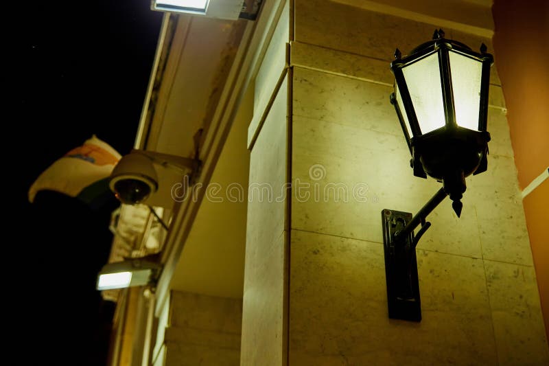 Ρετρό φανάρι στον τοίχο και φωτίζει την οδό σε μια σκοτεινή νύχτα στην παλιά πόλη στοκ φωτογραφία με δικαίωμα ελεύθερης χρήσης Ρετρό φανάρι στον τοίχο και φωτίζει την οδό σε μια σκοτεινή νύχτα στην παλιά πόλη στοκ φωτογραφία με δικαίωμα ελεύθερης χρήσης