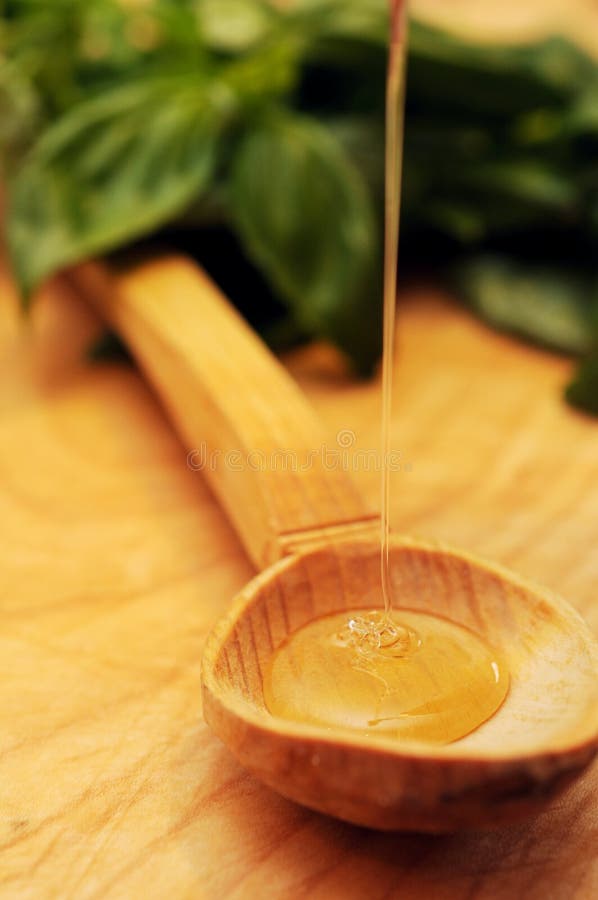 A stream of honey flowing into a wooden spoon. A stream of honey flowing into a wooden spoon.