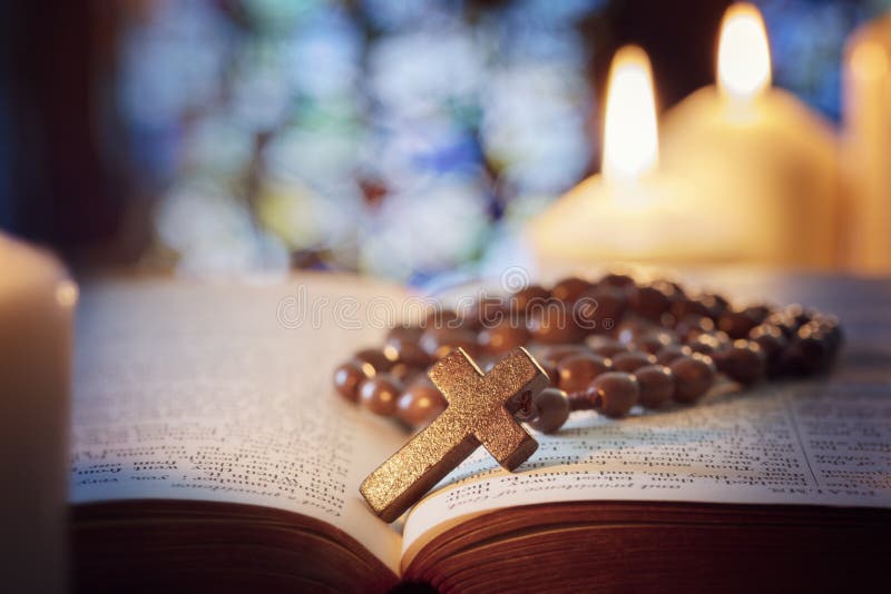 Rosary beads and crucifix cross on holy bible with candles in church. Rosary beads and crucifix cross on holy bible with candles in church