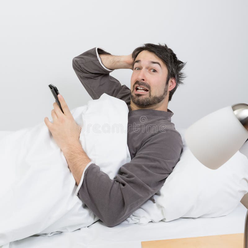 Man with beard lying in a bed with white bedding. Man with beard lying in a bed with white bedding