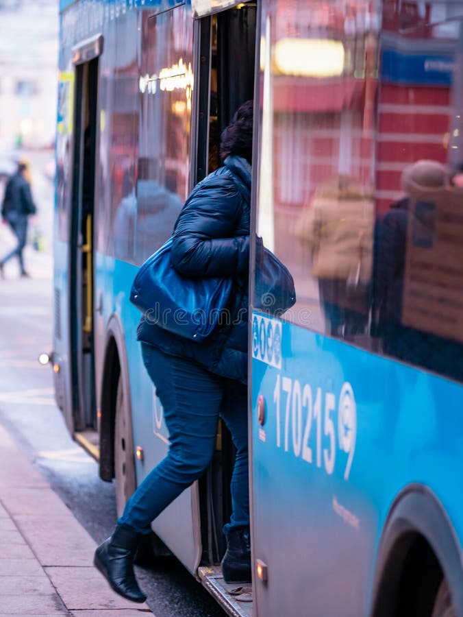 Moscow, Russia - January 17, 2020: The blue M27 bus pulls up to a public transport stop. City street with buses. Woman enter the door. Moscow, Russia - January 17, 2020: The blue M27 bus pulls up to a public transport stop. City street with buses. Woman enter the door