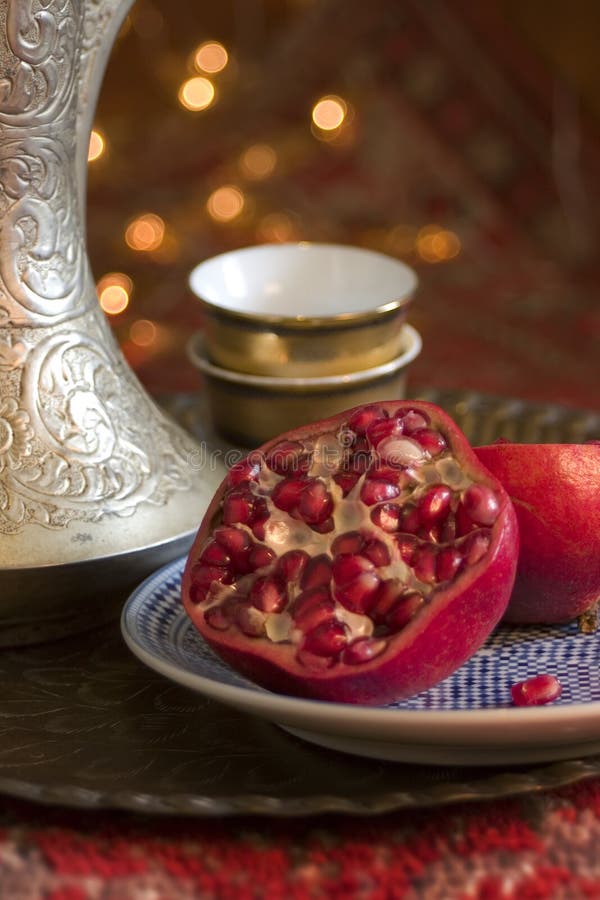 An open pomegranate on a plate, with Iranian jug and cups alongside. An open pomegranate on a plate, with Iranian jug and cups alongside