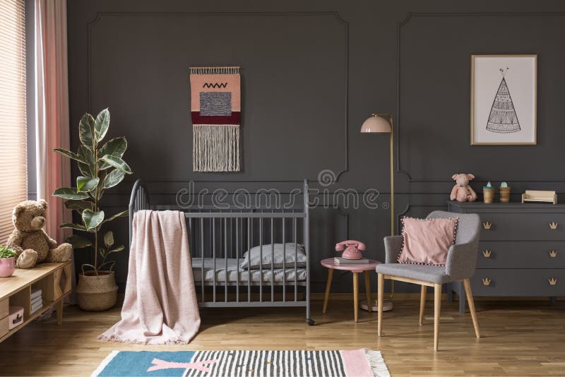 Pink pillow on grey armchair next to kid`s bed with blanket in bedroom interior with poster. Real photo. Pink pillow on grey armchair next to kid`s bed with blanket in bedroom interior with poster. Real photo