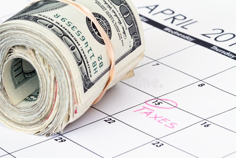 Cash money rolls on a calendar with reminder on the date to pay tax by. Cash money rolls on a calendar with reminder on the date to pay tax by