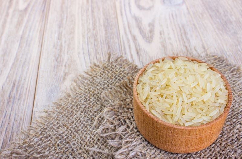 Ρύζι της Jasmine στο σάκο κύπελλων και burlap στον ξύλινο πίνακα στοκ φωτογραφία με δικαίωμα ελεύθερης χρήσης Ρύζι της Jasmine στο σάκο κύπελλων και burlap στον ξύλινο πίνακα στοκ φωτογραφία με δικαίωμα ελεύθερης χρήσης