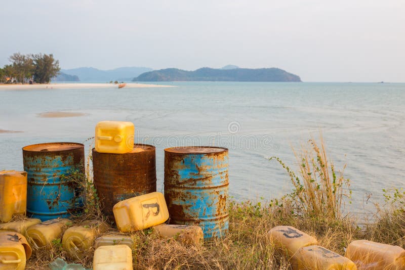 Three rusty barrels and plastic canisters next to a a tropical beach in Malaysia. Three rusty barrels and plastic canisters next to a a tropical beach in Malaysia