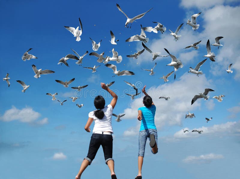 Girls feeding a flock of birds (seagulls) flying in the air. Girls feeding a flock of birds (seagulls) flying in the air