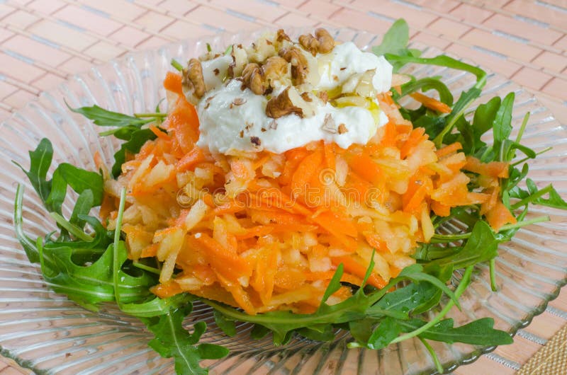 Two dishes of carrot and apple salad with cream and walnut in a diagonal arrangement. Two dishes of carrot and apple salad with cream and walnut in a diagonal arrangement