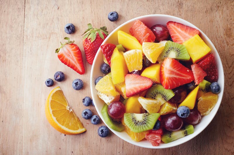 Bowl of healthy fresh fruit salad on wooden background. Top view. Bowl of healthy fresh fruit salad on wooden background. Top view.