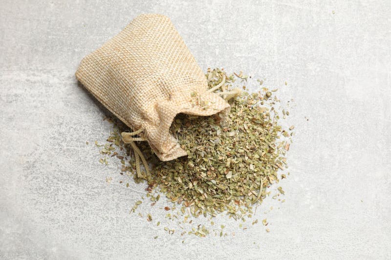 Σακί με αποξηραμένο oregano σε γκρίζα επιφάνεια τραπεζιού στοκ φωτογραφίες