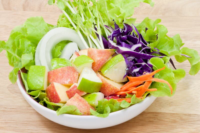 Green and red apple salad in bowl on wood background. Green and red apple salad in bowl on wood background