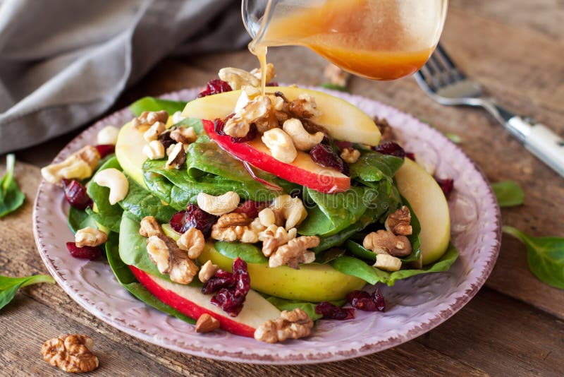 Apple cranberry spinach salad with balsamic vinaigrette on rustic wooden table. Apple cranberry spinach salad with balsamic vinaigrette on rustic wooden table