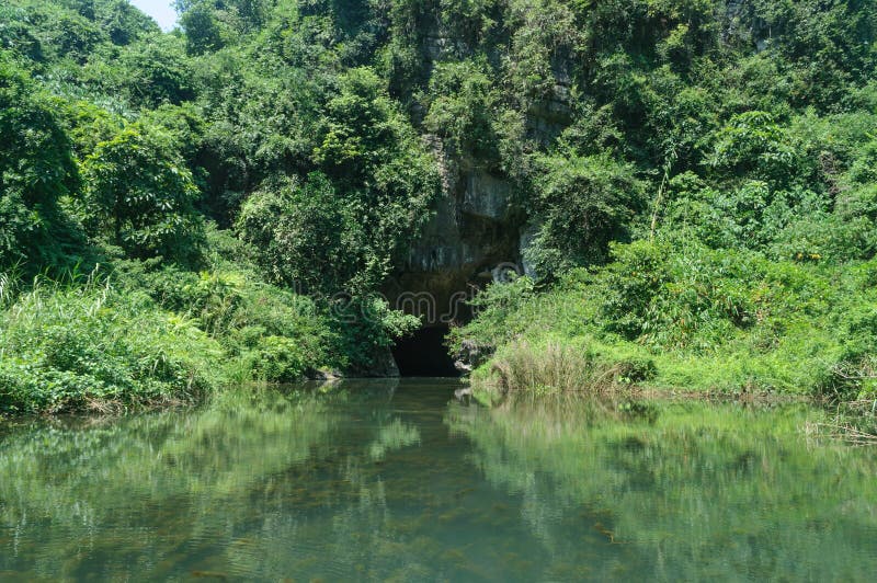 Tam coc, Vietnam; 08 10 2019: Sampan boat-ride, rowed by a villager at Tam Coc , Vietnam : the karst landscape with many vertical sides and covered by much green vegetation. Tam coc, Vietnam; 08 10 2019: Sampan boat-ride, rowed by a villager at Tam Coc , Vietnam : the karst landscape with many vertical sides and covered by much green vegetation.