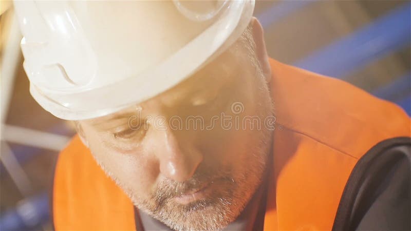Σε αργή κίνηση μέσης ηλικίας εργαζόμενος κινηματογραφήσεων σε πρώτο πλάνο στο άσπρο κράνος απόθεμα βίντεο