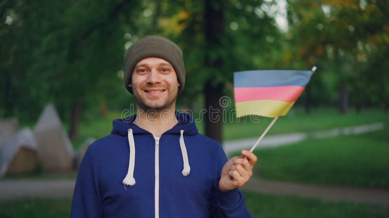 Σε αργή κίνηση πορτρέτο της αρσενικής γερμανικής κυματίζοντας σημαίας ατόμων αθλητικών τύπων όμορφης γενειοφόρου της Γερμανίας κα