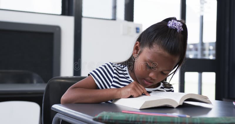 σε σχολική τάξη ένα κορίτσι με γεννήσεις επικεντρώνεται στην ανάγνωση βιβλίου