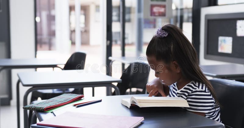 σε σχολική τάξη μια νεαρή αφρικανή αμερικανίδα επικεντρώνεται στην ανάγνωση με φωτοτυπικό χώρο