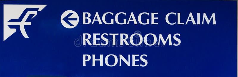 A baggage claim, restrooms, and telephone sign directing airport passengers. A baggage claim, restrooms, and telephone sign directing airport passengers.