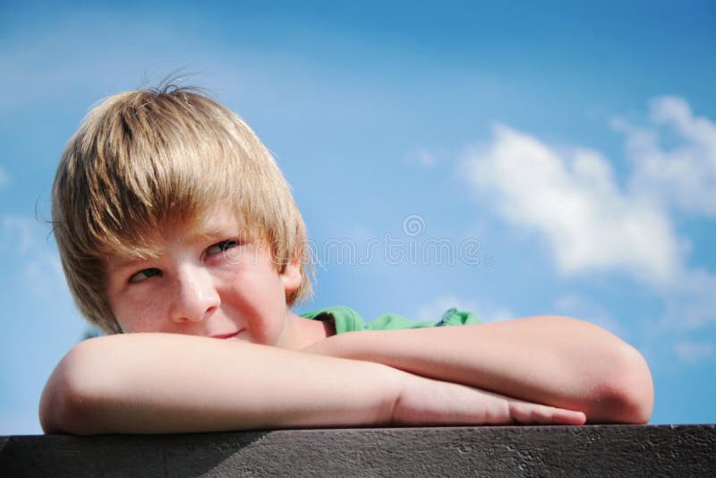 Young boy sitting on a bench thinking. Young boy sitting on a bench thinking