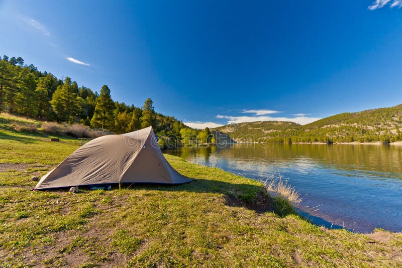 A camper's tent sits by the shore of a mountain Lake. A camper's tent sits by the shore of a mountain Lake
