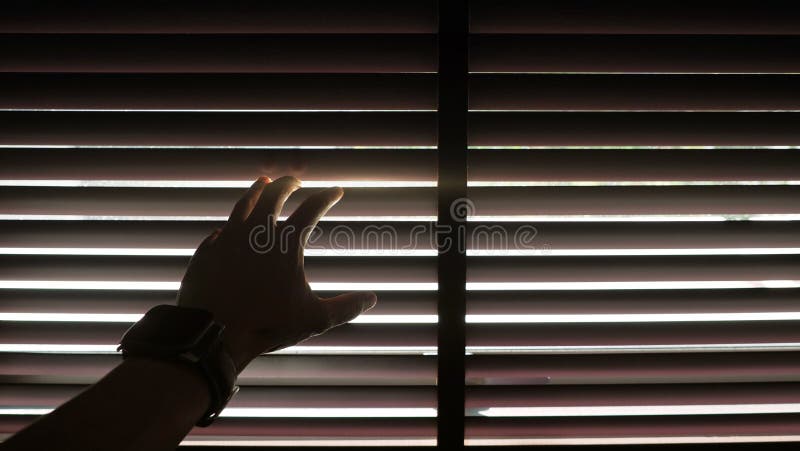 Σκιαγραφία ενός αρσενικού χεριού που φορά το ψηφιακό ρολόι που ανοίγει την ξύλινη τυφλή κουρτίνα με την επίδραση φωτός του ήλιου στοκ φωτογραφία με δικαίωμα ελεύθερης χρήσης Σκιαγραφία ενός αρσενικού χεριού που φορά το ψηφιακό ρολόι που ανοίγει την ξύλινη τυφλή κουρτίνα με την επίδραση φωτός του ήλιου στοκ φωτογραφία με δικαίωμα ελεύθερης χρήσης