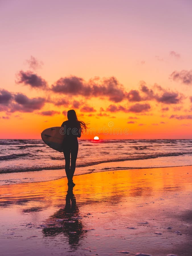 Σκιαγραφία του κοριτσιού surfer με την ιστιοσανίδα σε μια παραλία στο ηλιοβασίλεμα Surfer και ωκεανός στοκ εικόνες με δικαίωμα ελεύθερης χρήσης