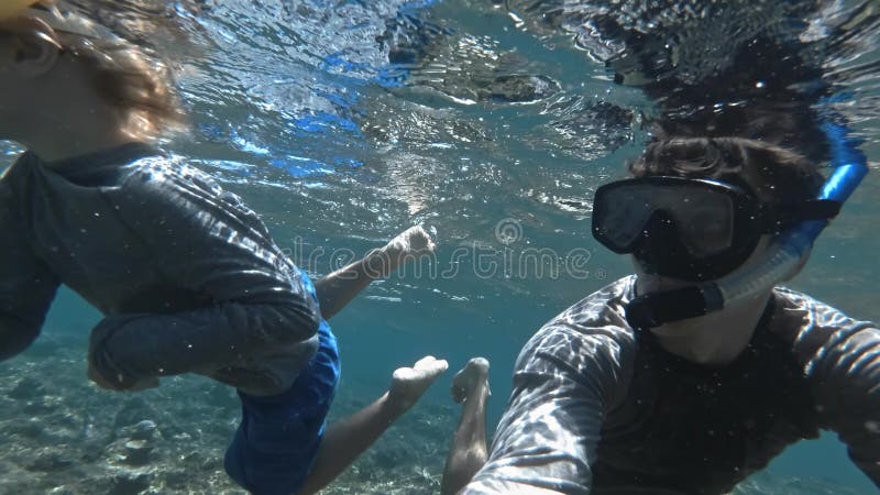 Σνορκέλινγκ παιδιά βουτάνε με τον πατέρα τους σε καθαρό γαλάζιο νερό με ψάρια
